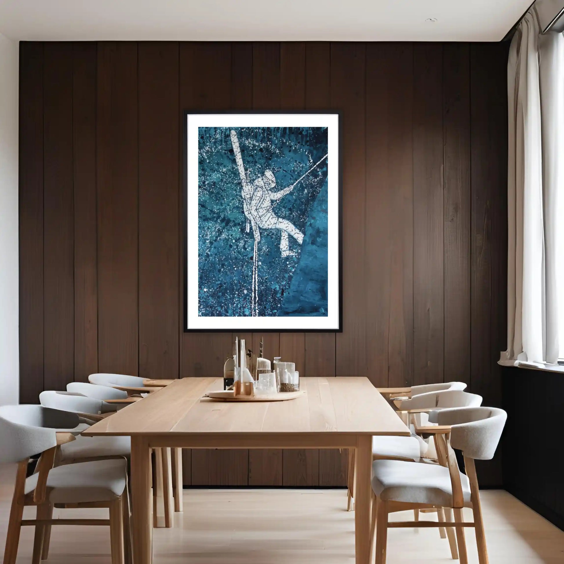 Dining room with wooden table and chairs, framed ski artwork on the wall.