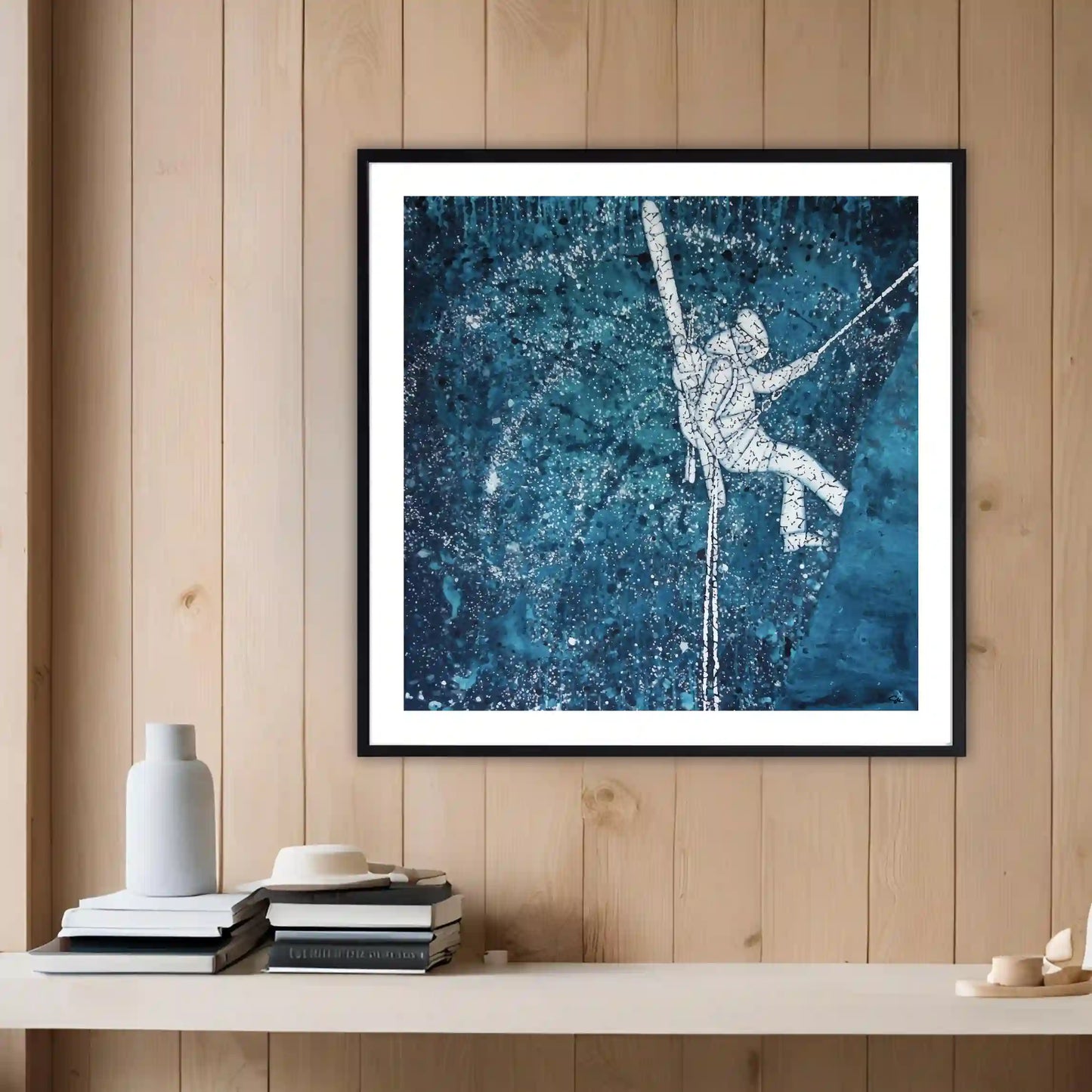 Framed artwork of an astronaut on a blue starry background hanging on a wooden wall.